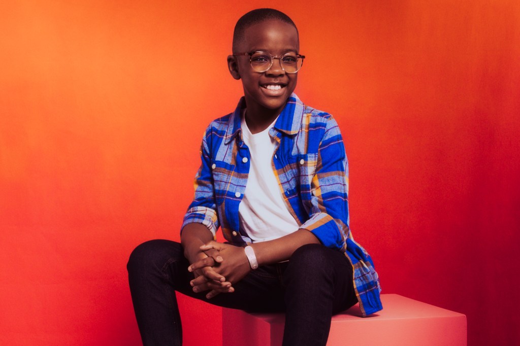 boy with blue and white shirt sitting in front of orange background