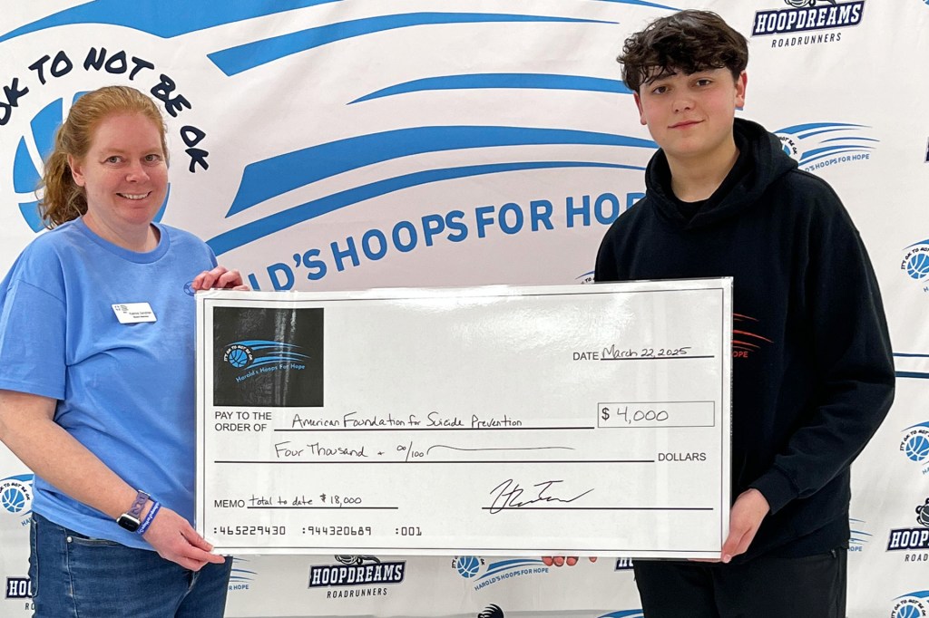 A woman and a teenage boy hold a large check for four thousand dollars made out to the American Foundation for Suicide Prevention.