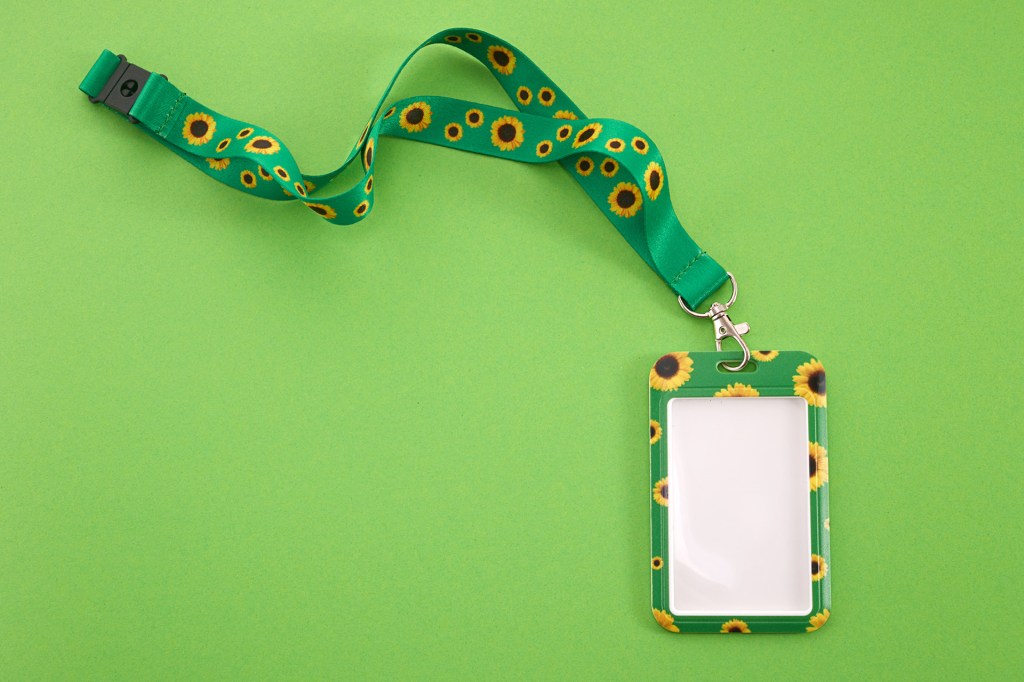 A green lanyard and ID card holder with a sunflower pattern on a green background