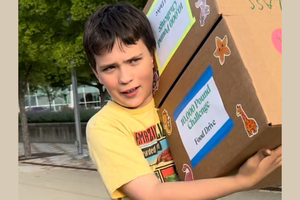 Boy in a yellow shirt carries two large boxes labeled “10,000 Pound Challenge Food Drive,” decorated with stickers.